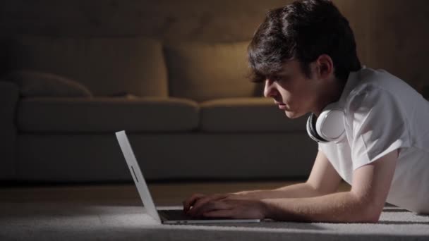 10代の男の子が夜にノートパソコンを入力します 居間で働く者 — ストック動画
