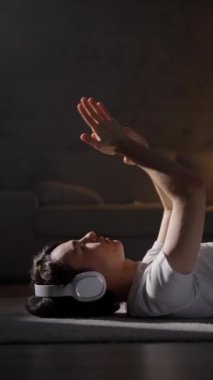 Sevimli genç çocuk yerde uzanmış, gevşeyen ve ellerini hareket ettiren müzik dinliyor.