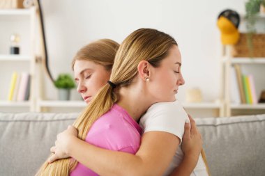 Birbirlerini kucaklayan ve rahatlatan iki genç kadın. Ruh sağlığı konsepti