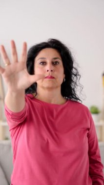 Orta yaşlı olgun bir kadın avuç içiyle dur işareti yapıyor. Cinsiyet şiddeti ve istismar kavramı