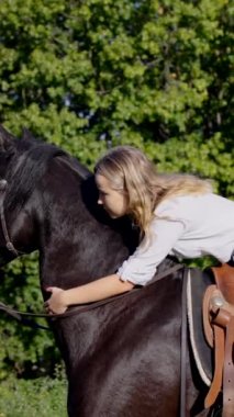 Siyah atı kucaklayan ve okşayan genç bir kadın..