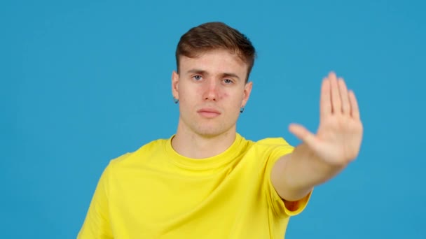 Mladý Muž Dělá Stop Signál Rukou Izolovanou Modrém Pozadí Koncept — Stock video