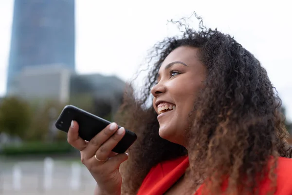 Positive African American woman using phone. Black curvy businesswoman recording voice message or reminder on smartphone