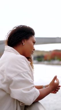 Üzgün Afrikalı Amerikalı kadın nehrin kenarında açık havada düşünüyor.