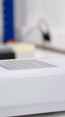 Test yapmak için numuneleri makineye koyan bir bilim adamının elleri.
