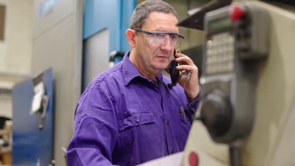 一个成熟的工程师在Cnc工厂使用自动售货机工作时使用电话的视频 — 图库视频影像