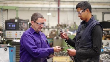 Cnc fabrikasında üretilen metal parçalarının kalitesini kontrol eden iki işçinin videosu