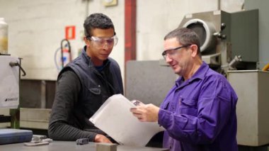 Olgun bir mühendisin genç bir işçiye talimat verirken videosu.