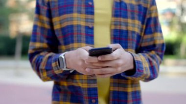 Açık havada yürürken telefonu kullanan genç bir İspanyol 'un ağır çekimde çekilmiş yatay yakın çekim videosu.