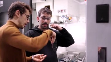 Bir mühendisin el işçisine CNC fabrikasındaki endüstriyel süreçten bahsederken videosu.