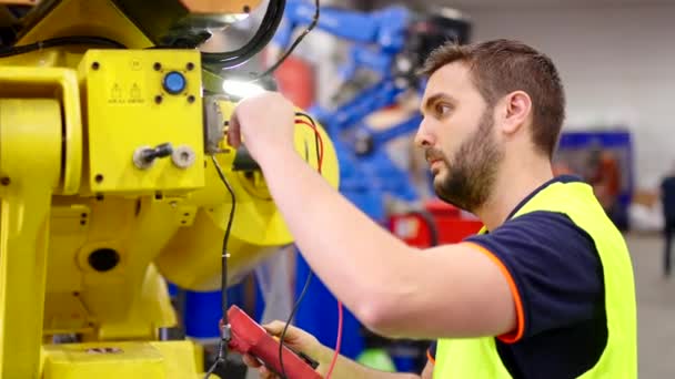 工場でテスターを使用する専門の電気技師 産業用ロボットで働くメンテナンスエンジニア — ストック動画
