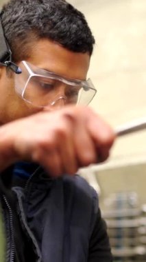Koruyucu gözlüklü bir adamın CNC fabrikasındaki bir değirmen makinesini kullanışının videosu.
