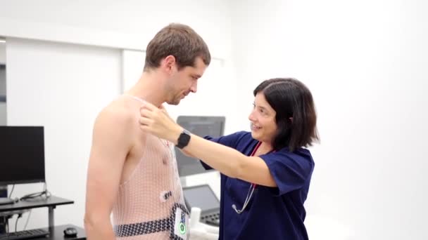 心臓ストレス検査を実施するために患者にメッシュを貼る看護師のビデオ — ストック動画