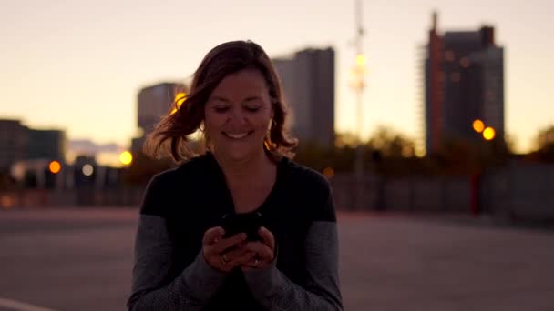 一个快乐的跑步者运动后在日落时使用电话的视频 — 图库视频影像