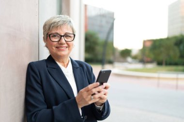 Açık havada telefon kullanan gülümseyen bir iş kadınının fotokopi çekilen yatay fotoğrafı