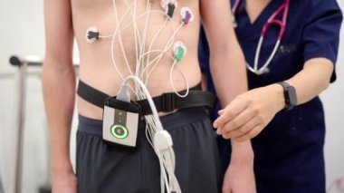 Stres testi yapmaya hazır bir hastanın kemerine bağlı bir kardiyak Holter monitörü.