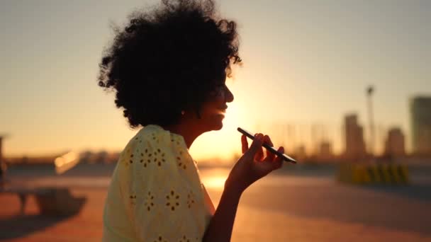 一个非洲女人在日落时坐在城市里用流动扬声器讲话的视频 — 图库视频影像