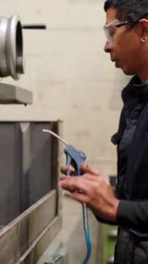 Fabrikadaki bir makinenin kalan suyunu temizleyen bir işçinin videosu.