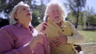 Yaşlı adam parkta kalp krizi geçirirken endişeli, olgun bir kadının acil durum çağrısı videosu.