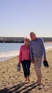 Yetişkin bir çiftin kumsalda yalınayak dolaşırken ki yavaş çekim videosu.