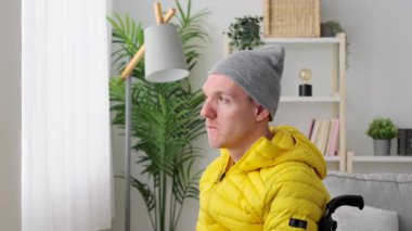 Engelli, düşünceli bir adam, tekerlekli sandalyede oturup pencereden bakıyor. Beyin felci ve yalnızlık kavramı