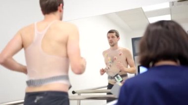 Yoğunlaşmış bir adamın bir doktorun yanında kardiyak stres testi yaparken videosu.