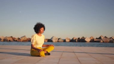 Denizin kenarında meditasyon yapan Afrikalı bir kadına yaklaşan video.