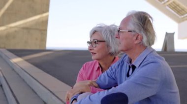 Yaşlı bir çiftin yavaş çekim videosu. Bir bakış açısına göre şehirde oturup manzaranın tadını çıkarıyorlar.