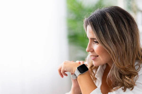 Close-up of a woman asking question to a smart watch at home