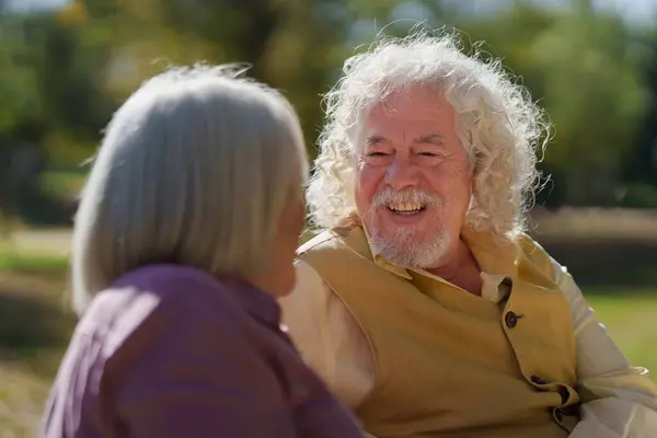Laughing senior man talking to wife in a park