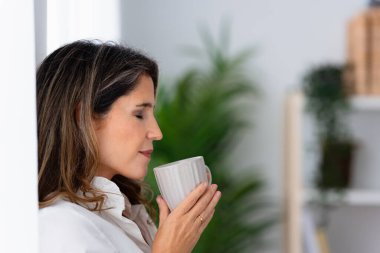 Kadın evde duran kahvenin kokusunu kokluyor.