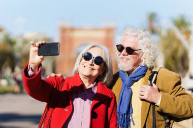 Barselona 'da kıdemli turist çifti gülümsüyor ve selfie çekiyor.