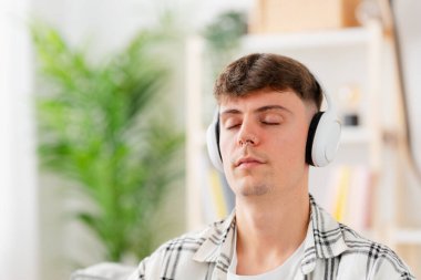 Rahatlatıcı müzik dinlerken meditasyon yapan genç adamın yakın çekimi.