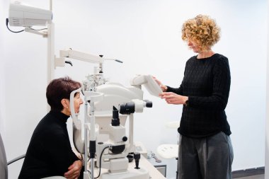 Göz doktoru kadın görme tanısı için hastaya retinografi yapıyor..