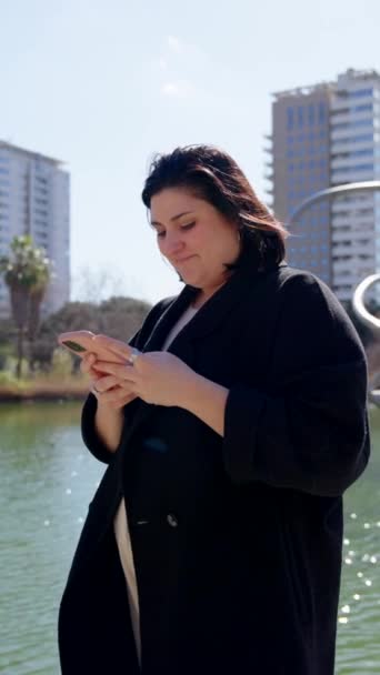 Curvy Γυναίκα Χρησιμοποιώντας Τηλέφωνο Εξωτερικούς Χώρους Ένα Πάρκο — Αρχείο Βίντεο