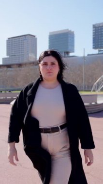 Güçlü kıvrımlı kadın kameraya bakıyor. Şehirde yürüyen kendine güvenen biri..