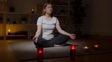 Evde meditasyon yapan genç bir kadın yerde oturuyor. Nilüfer çiçeği pozunda nefes alan genç..
