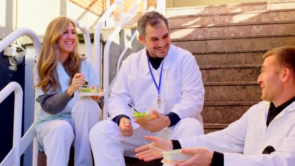 外で休憩する病院の労働者のグループ 外で階段に座っている医師 — ストック動画