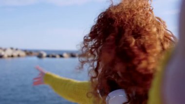Genç mutlu kızıl saçlı kadın kamerayla konuşuyor. Genç nüfuzlu biri açık havada canlı yayında. Video görüşmesi yapan bir turist..