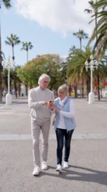 Yaşlı turist çift yürürken telefonla GPS kullanıyor.
