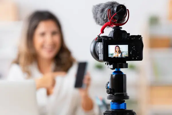 Focus on the camera and microphone used by a woman recording a video tutorial from home