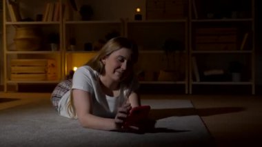 Geceleri telefon kullanan genç bir kadın. Ergenlik dönemi mesajları evde yerde yatıyor.