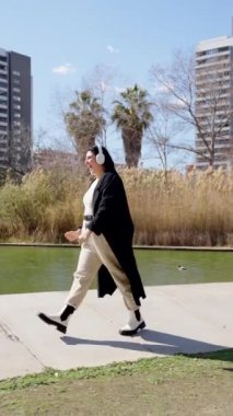 Açık havada müzik dinleyen mutlu kavisli kadın. Parkta yürürken dans eden biri