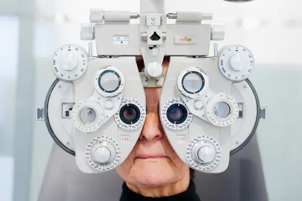 老年病人在眼科诊所使用屈光镜的前视 免版税图库图片