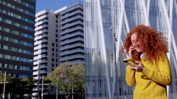 Şehirde Yürürken Telefon Kullanan Kızıl Saçlı Genç Bir Kadın — Stok video