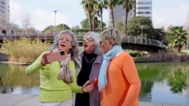 Küçük bir grup olgun kadın parkta selfie çekiyor. Üst düzey turistler dışarıda eğleniyor..