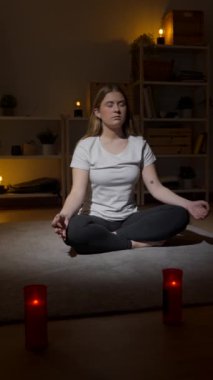 Evde meditasyon yapan genç bir kadın yerde oturuyor. Nilüfer çiçeği pozunda nefes alan genç..