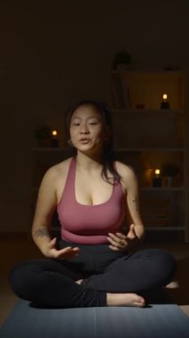 Genç Çinli yoga hocası gece kamerayla konuşuyor.