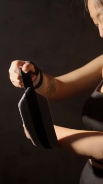 Tanımlanamayan bir kadın koyu arkaplanda spor bilekliği takıyor..