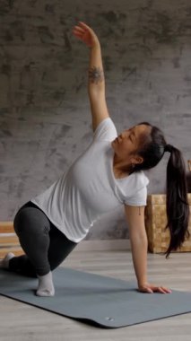 Genç Çinli kadın evde pilates egzersizi yapıyor. Kapalı alanlarda gerinen kişi.